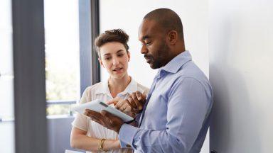 Coworkers standing up and looking at tablet together